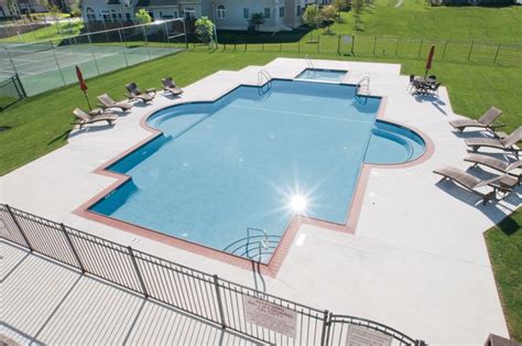 An Aerial View Of A Swimming Pool With Lounge Chairs And Tennis Court