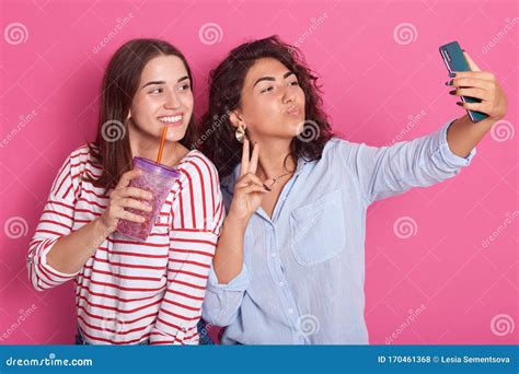 Horizontal Shot Of Two Girls Friends Taking Selfie With Smartphone