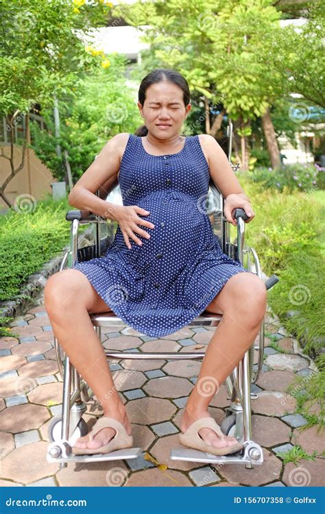 Pregnant Woman With Tummy Ache On Wheelchair At The Garden Stock Photo