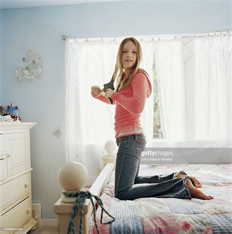 Teenage Girl Brushing Hair Kneeling On Bed Portrait Side View Photo