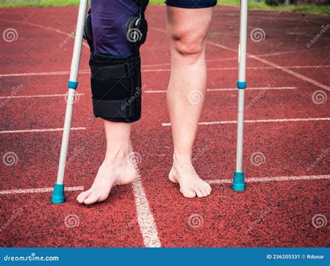 Woman Athlete On Crutches Wearing A Wrist Brace And Knee Support Stock