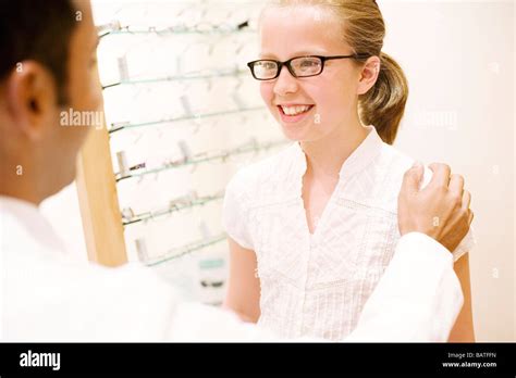Choosing A Pair Of Glasses Optician Helping A Ten Year Old Girl Choose Apair Of Glasses Stock