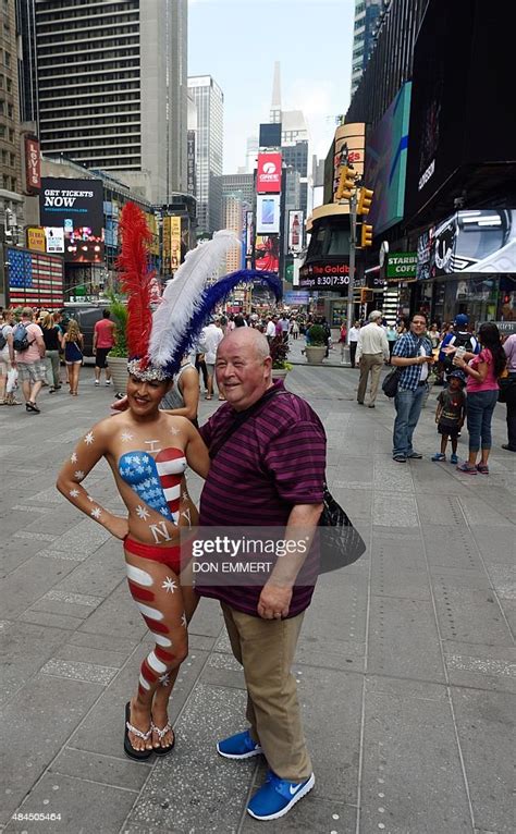 A Young Woman Poses With Tourists In Times Square Wearing Body Paint