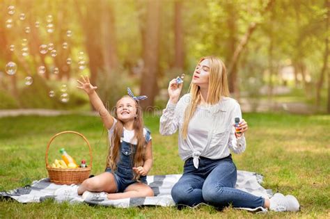 Mother And Daughter On Picnic Having Fun Blowing Bubbles Outdoors Stock