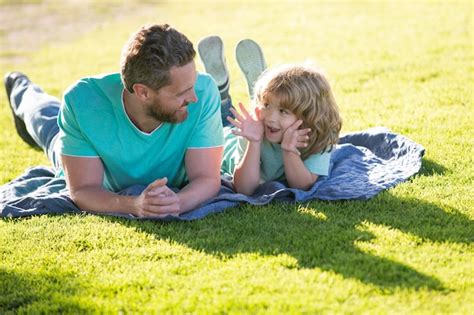 Premium Photo Happy Father And Son Enjoying Summer Time Laying On Grass Vacation In A Sunny Park