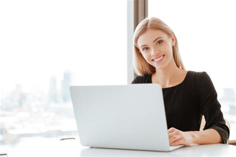Picture Of Cheerful Young Lady Worker Sitting In Office While Using