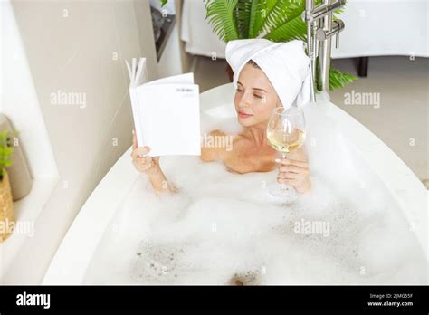 Beautiful Happy Young Woman Lying In Bath With Foam Reading Book And
