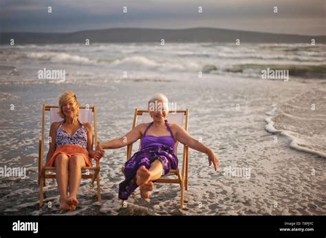 Two Happy Mature Women Relaxing In Deck Chairs On The Beach Stock Photo Alamy