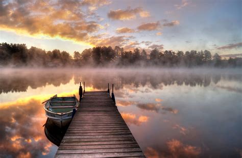 Download 1080x1920 Pier Lake Reflection Boat Fog Sunrise Trees