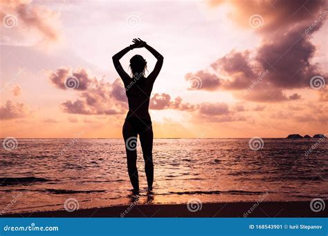 Silueta De Mujer Con Brazos Levantados Contra La Tranquila Playa De