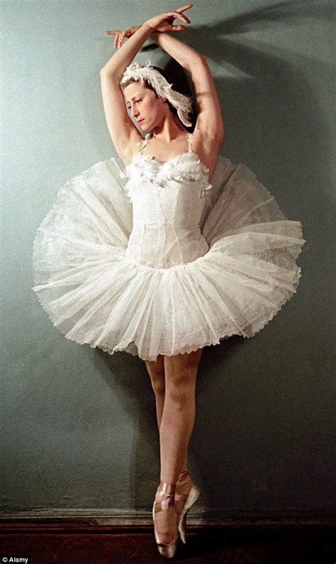 a woman in a white tutu is posing for the camera with her hands behind her head