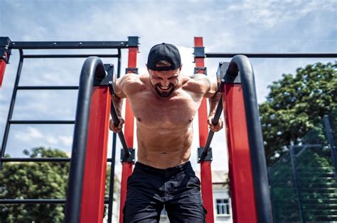 Forte Homem Musculoso Fazendo Flexões Em Barras Assimétricas No Ginásio