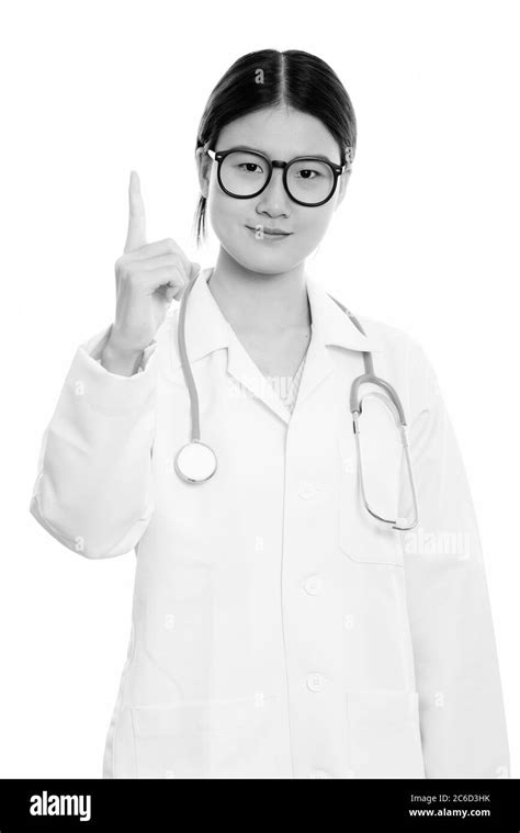 Studio Shot Of Young Beautiful Asian Woman Doctor Pointing Finger Up