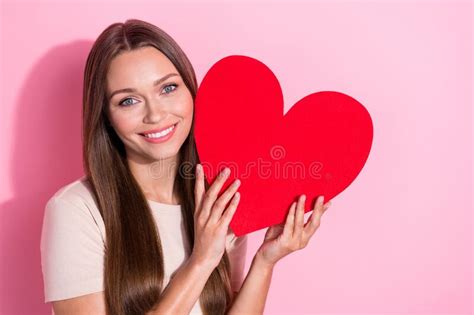 Photo Of Positive Adorable Lady Hands Hold Paper Heart Symbol Beaming Smile Isolated On Pink