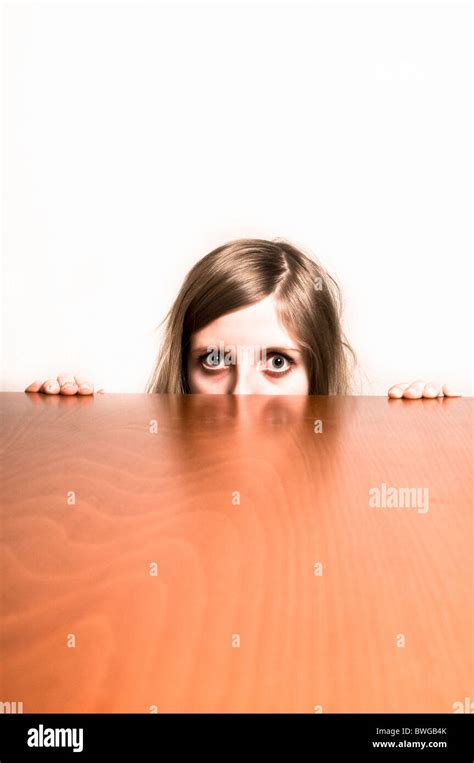 Blond Girl Hiding Behind A Table Afraid Or Shy Stock Photo Alamy