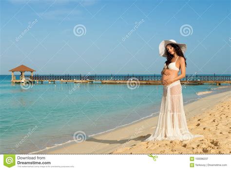 beautiful pregnant woman on a sandy beach hugging her tummy dominican republic the caribbean