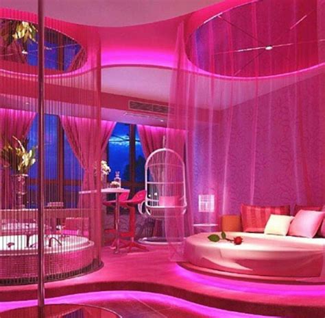 A Living Room With Pink Lighting And Round Couches In The Center Surrounded By Curtains