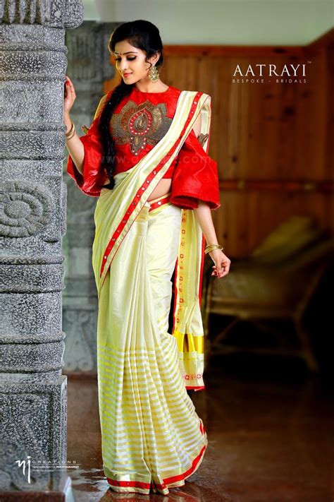 A Woman In A Red And White Sari Standing Next To A Stone Pillar With Her Hand On Her Hip