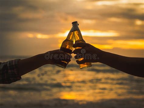 Couple Hands Holding Beer Bottles And Clanging On The Sunset Beach Party Holiday Summer