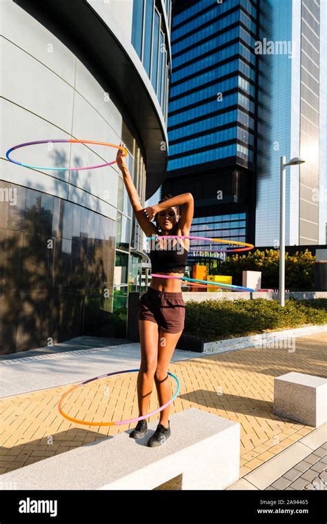 Young Woman Performing Hula Hoop Dance With Four Rings In Urban Area