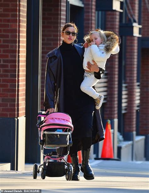 irina shayk is one multi tasking mom as she carries daughter lea and pushes