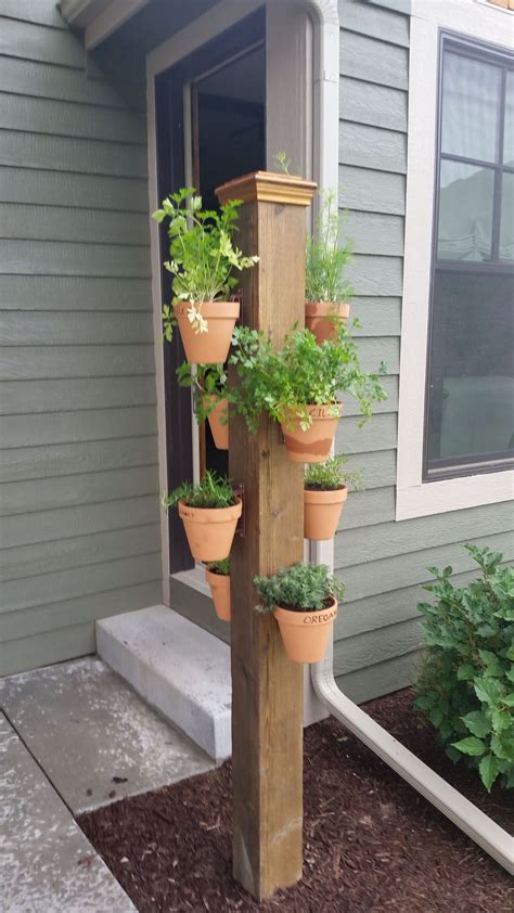 A Wooden Pole With Potted Plants On It In Front Of A House And Steps