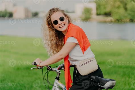 Outdoor Shot Of Pleased Active European Woman With Curly Bushy Hair