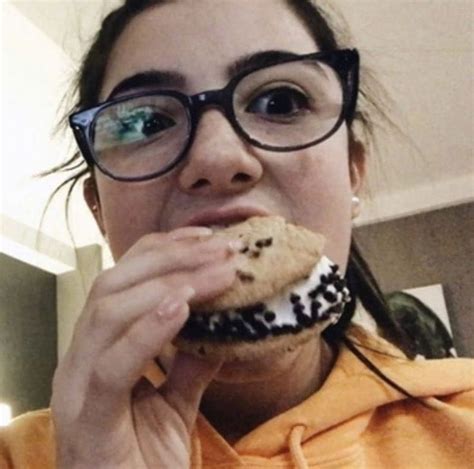 A Woman Wearing Glasses And Eating A Cookie