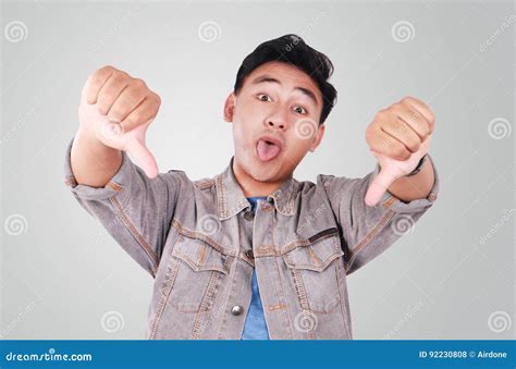 Young Asian Guy Mocking Gesture With Thumbs Down Stock Photography