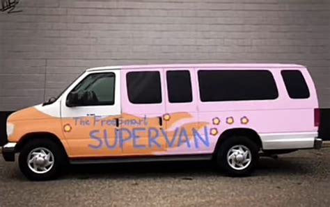 An Orange And Pink Van Parked In Front Of A Brick Wall With The Words