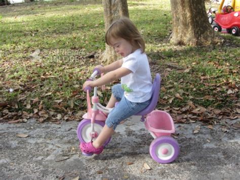 Family is playing with child walking down road in city park. Riding A Bike Isn't So Easy.... #DownSyndrome # ...
