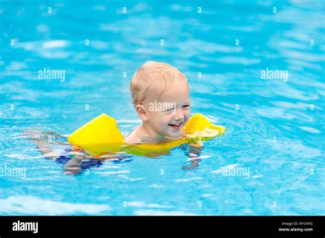 Baby With Inflatable Armbands In Swimming Pool Little Boy Learning To