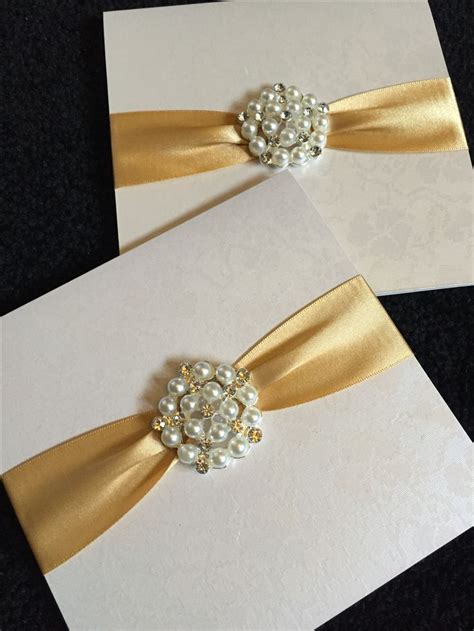 Two White Cards With Gold Ribbons And Pearls
