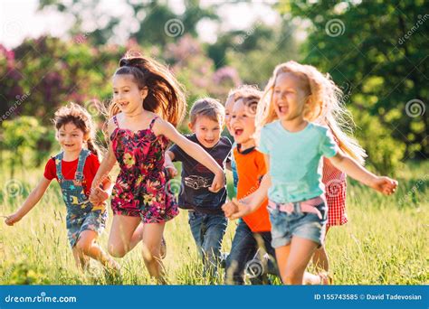 Large Group Of Kids Friends Boys And Girls Running In The Park On