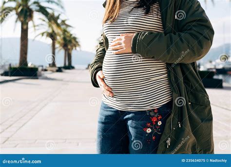 Pregnant Woman Hugs Her Belly With Her Hands While Standing On The