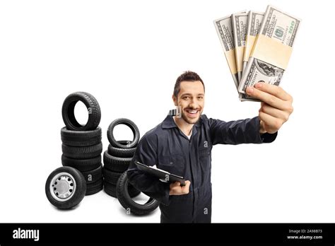 Auto mechanic with a clipboard holding stacks of money and tires behind