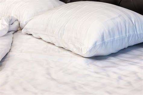 Two White Pillows With White Bedding Sheet On Empty Bed In Bedroom