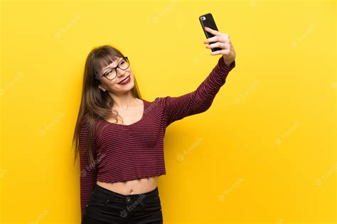 premium photo woman with glasses over yellow wall making a selfie