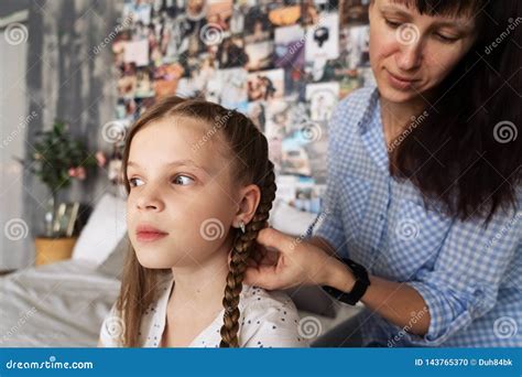 Mom Carefully Braids Her Beloved Daughter`s Hair In Braids On Her Head
