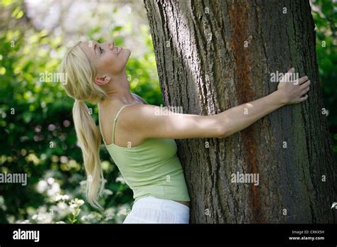 A Young Blond Woman Hugging A Tree Looking Upwards Stock Photo Alamy