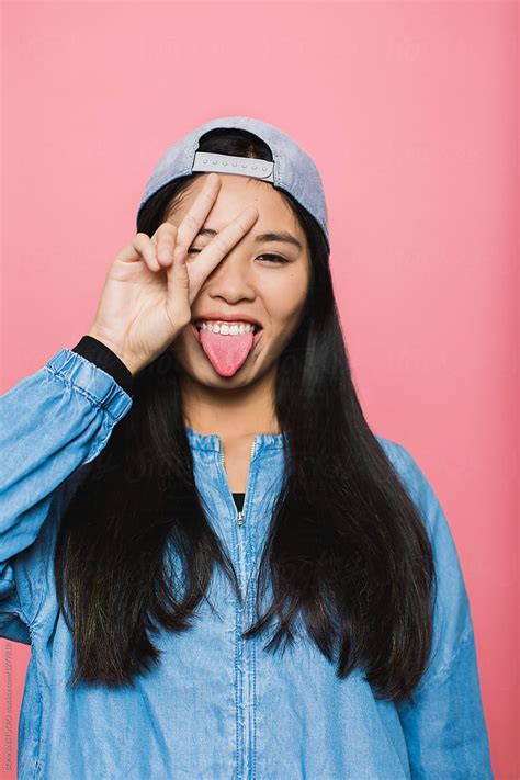 Teen Asian Girl Giving Hand Sign Over Pink Portrait By Stocksy