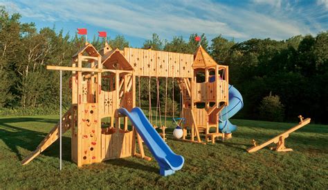 A Wooden Play Set In The Grass With A Blue Slide And Climbing Frame On It