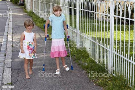 Girl With Crutches Besides Her Little Sister Stock Photo Download