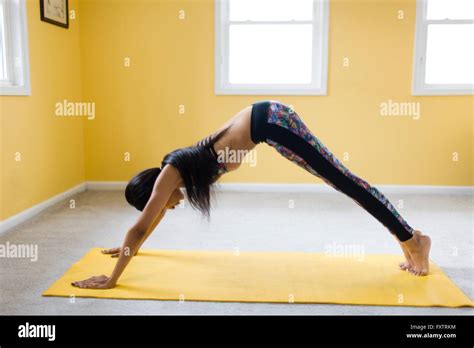 Young Woman Bending Over In Yoga Pose On Yoga Mat Stock Photo Alamy