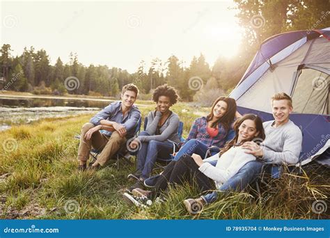 Friends On A Camping Trip Relaxing By A Tent Look To Camera Stock Photo