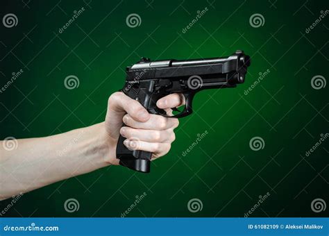 Firearms And Murderer Topic Human Hand Holding A Gun On A Dark Green