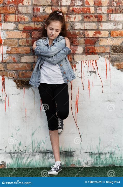 Portrait Of A Beautiful Teenage Girl Posing Against A Brick Wall Stock