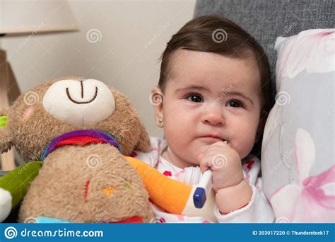 Sick Baby Girl With Thermometer In Mouth Holding Teddy Bear Stock Photo