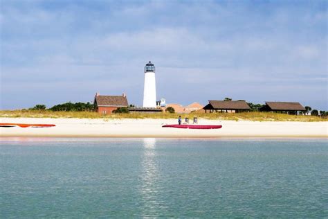 Two Canoes Are Sitting On The Beach In Front Of A Light House And Water