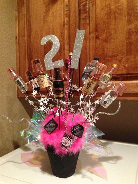 a vase filled with lots of liquor bottles and some pink feathers sitting on top of a table